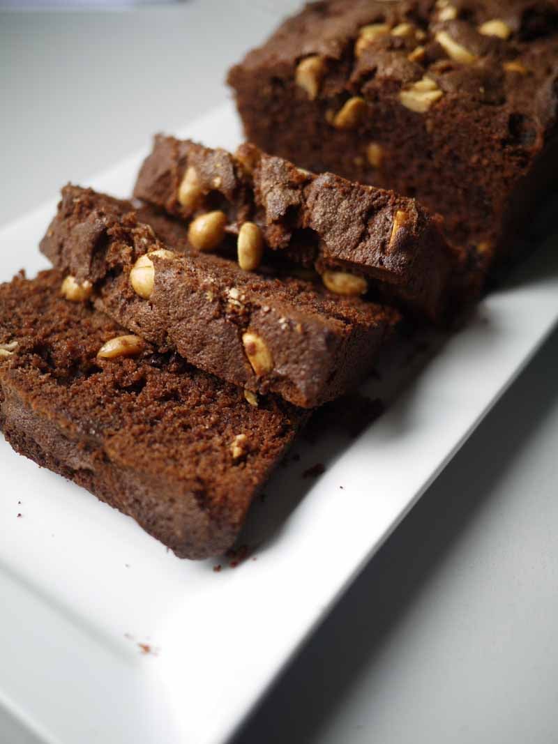 Close up view of sliced salted chocolate and peanut butter sponge cake on a white plate.