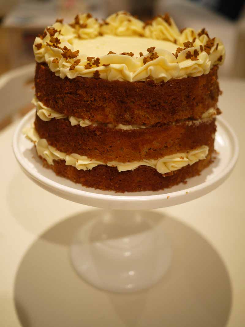 side view of 3 tier gingerbread latte layer cake on a white cake stand