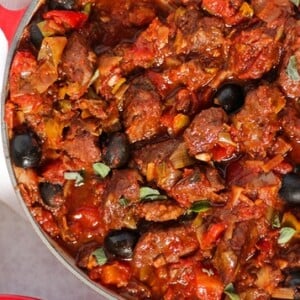 Greek pork casserole in a le creuset pan with olives and oregano