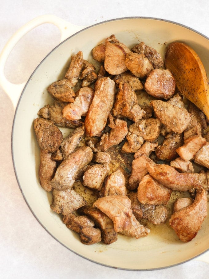 Pieces of pork browned in a le creuset frying pan