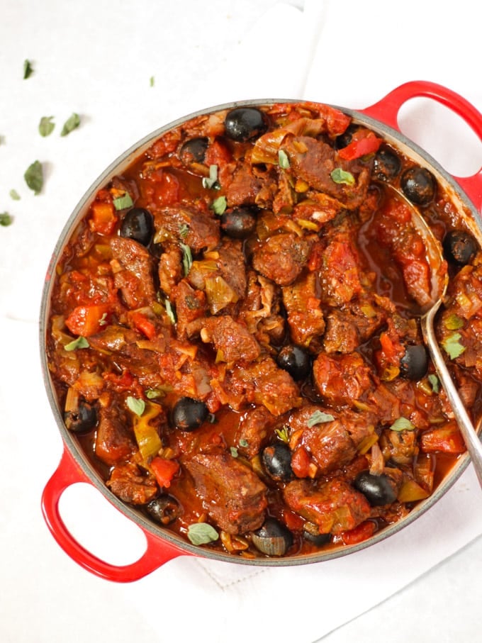 Slow cooked pork casserole with tomato greek sauce in a red le creuset pan