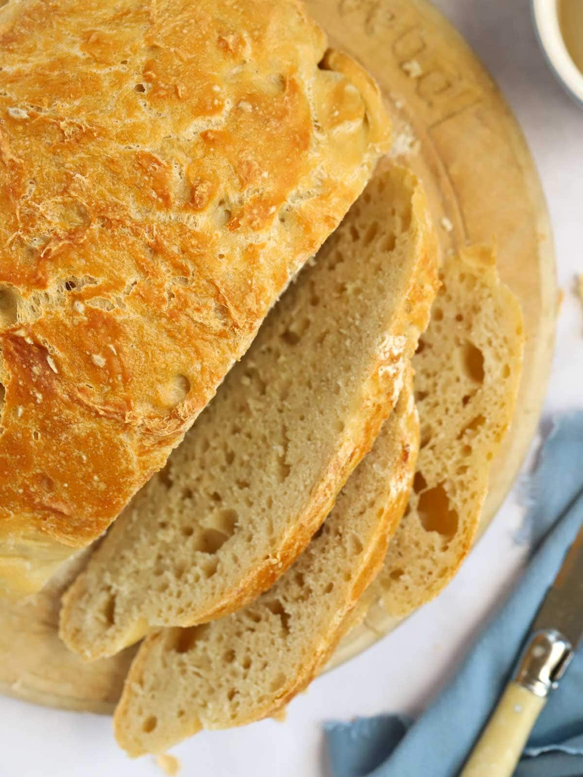 Cut loaf of homemade overnight No Knead Bread loaf on a chopping board.