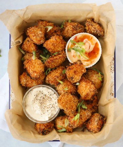 Popcorn chicken pieces with dips in a tray.