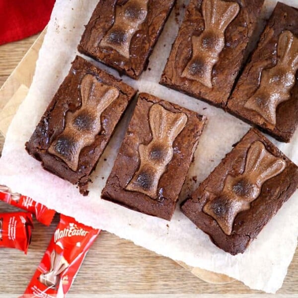 chocolate brownies topped with malteser bunnies on a white cloth with a wooden background