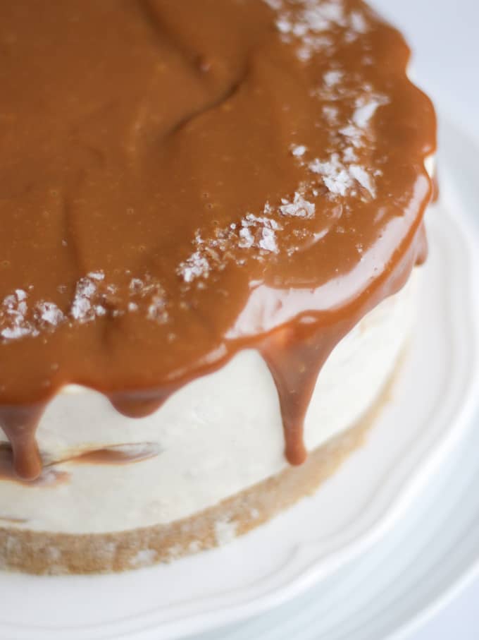 Side view of salted caramel cheesecake with dripping caramel on a white plate.