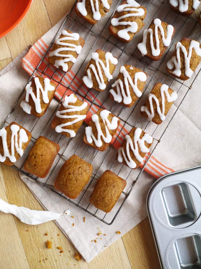 Mini Pumpkin Bread Spiced Loaves cooling on a wire rack straight out of the oven, drizzled with icing sugar.