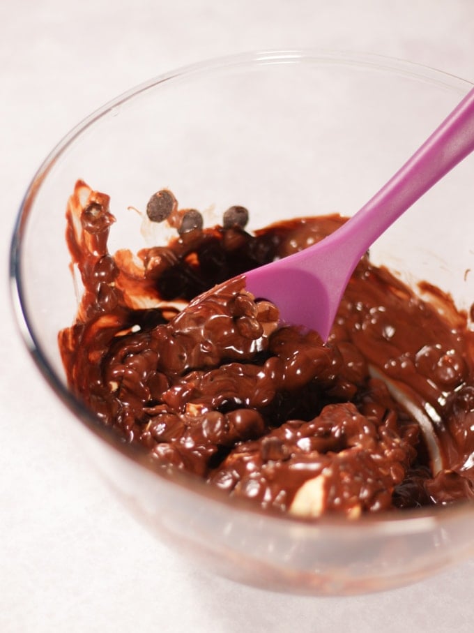 Glass bowl with ingredients for Creme Egg Rocky Road in (chocolate, butter and golden syrup) with purple spoon.