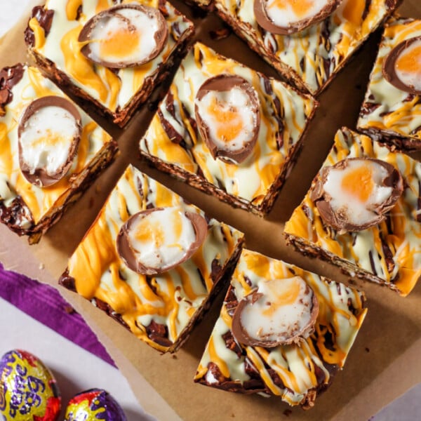 Pieces of creme egg rocky road chocolate squares on chopping board.