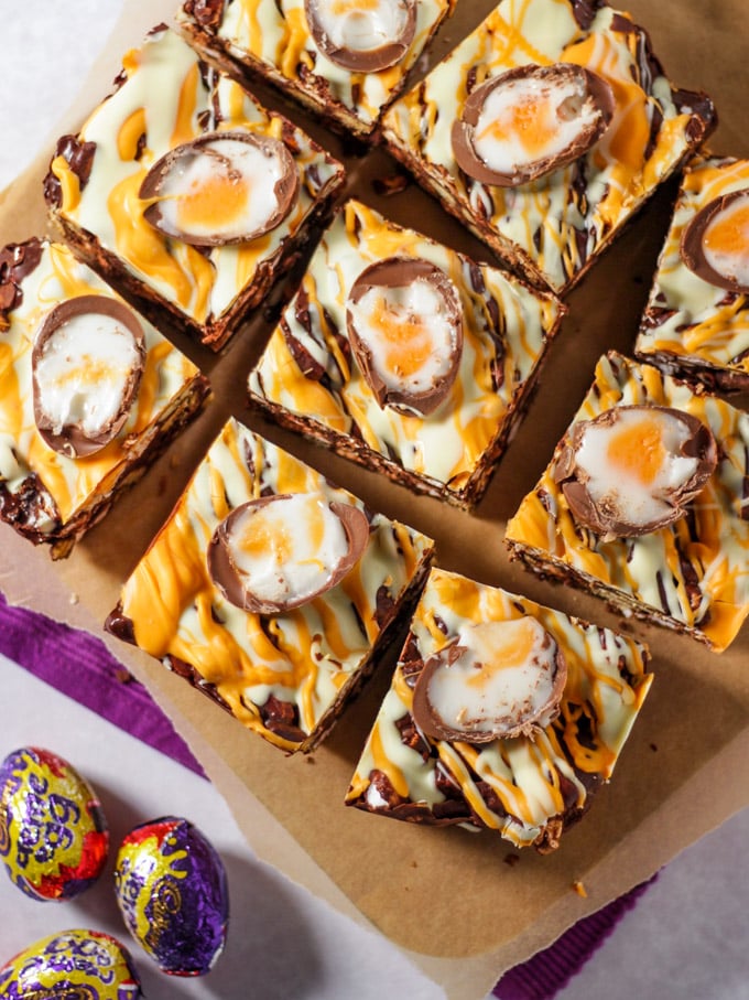 Pieces of creme egg rocky road chocolate squares on chopping board.