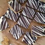 A slab of peanut butter bars cut into 12 squares on a chopping board.