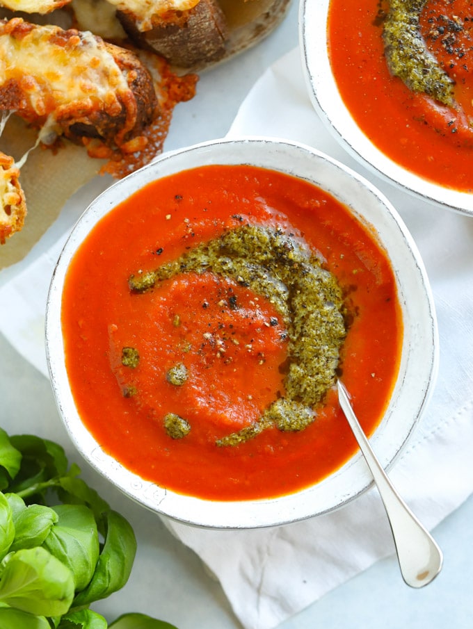 Easy tomato soup recipe with a swirl of pesto in a white bowl