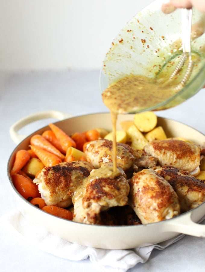 Browned chicken thighs and carrots having sauce poured over.