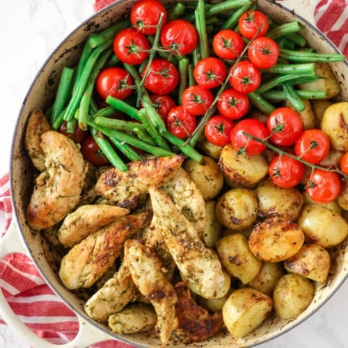 Pesto chicken bake in a dish with green beans, tomatoes and potatoes