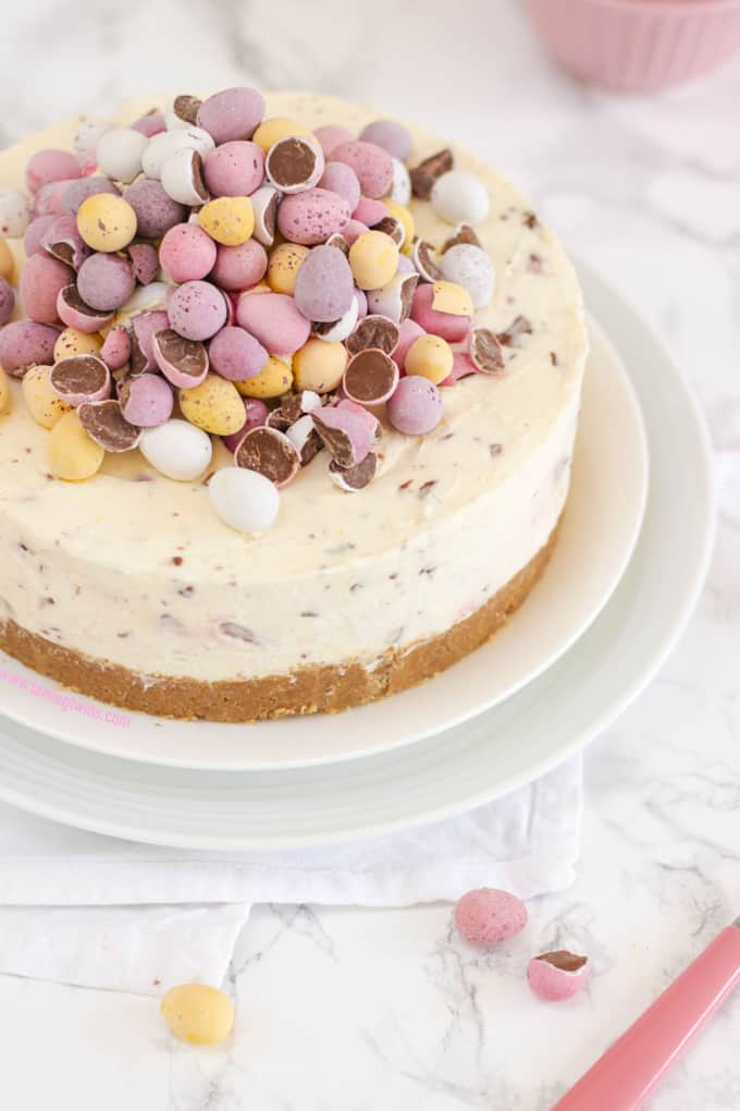 Mini Candy Egg Cheesecake on two white plates with marble background.