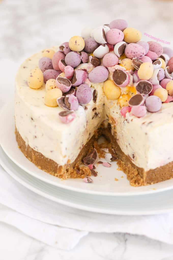 Mini Egg Cheesecake with a slice taken out on two white plates on top of a napkin.