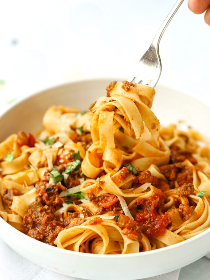 A fork lifting spaghetti bolognese from a bowl.