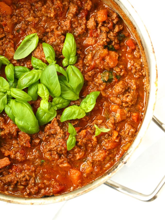 Large saucepan of beef bolognese sauce recipe for spaghetti bolognese with basil.