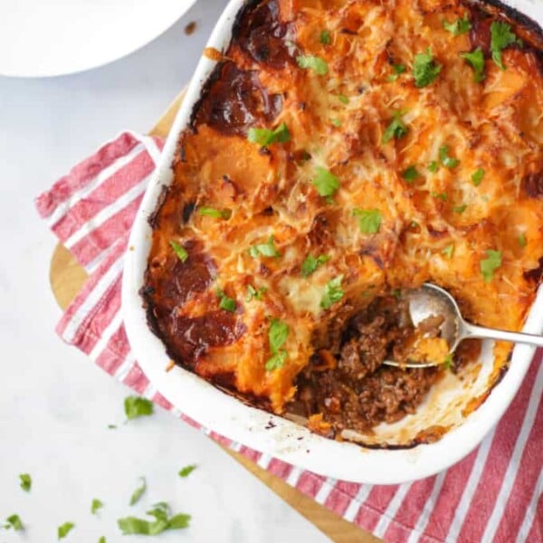 Overhead photo of sweet potato cottage pie with a spoonful taken out on a red and white fabric.