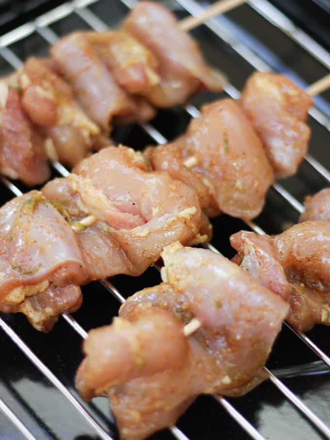 Chicken satay skewers on a black grill pan raw ready to be cooked.