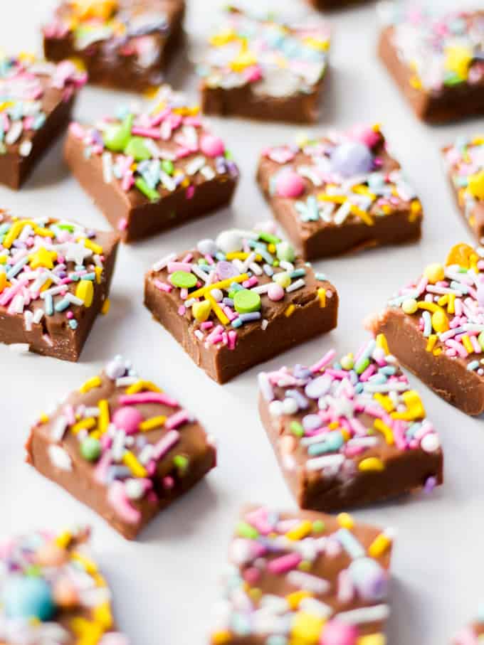 Cubes of milk chocolate microwave fudge with brightly coloured sprinkles on top, side view.