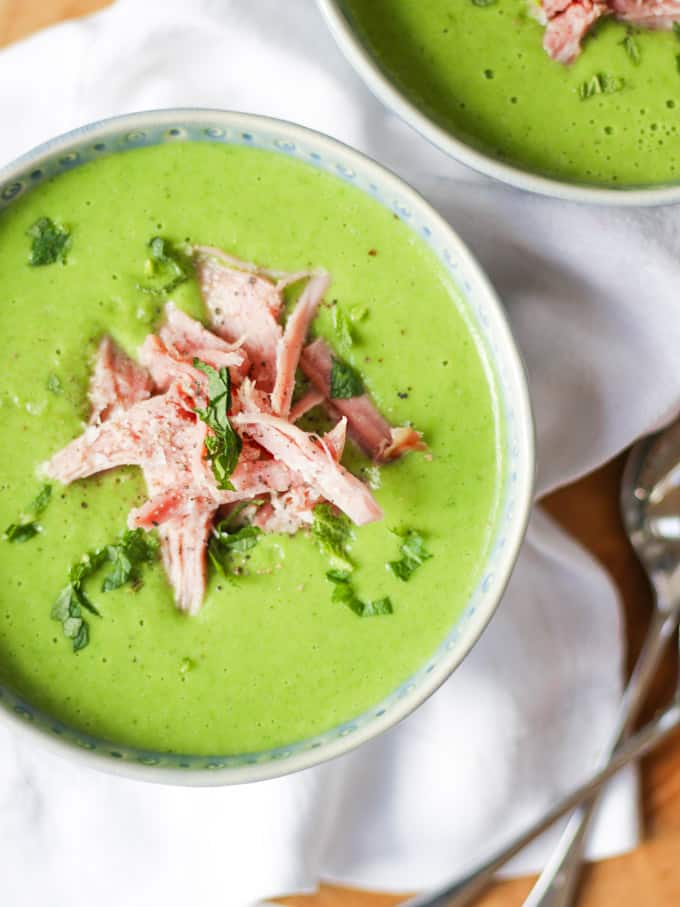 Close up overhead photo of pea and ham soup with mint and white napkin.