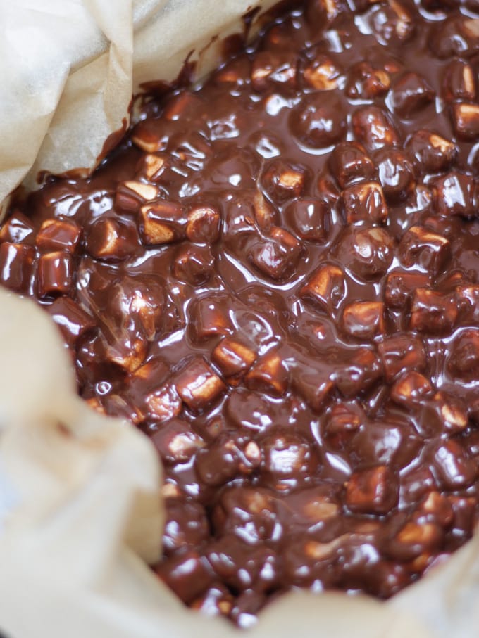 Dark chocolate with marshmallows mixed in for rocky road in baking paper lined dish overhead shot, for Malteser Rocky Road recipe.