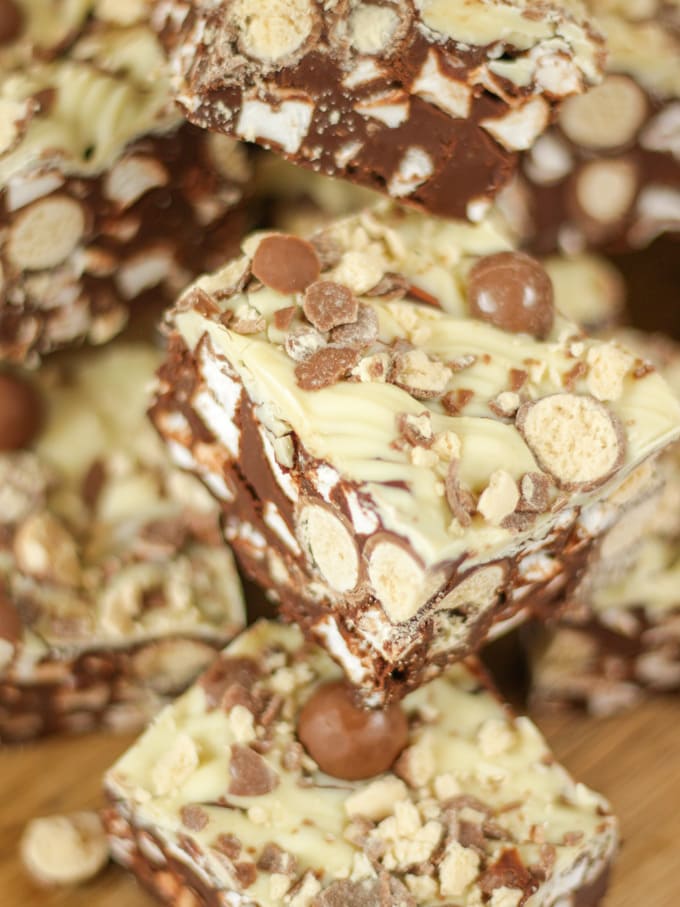 Close up photo of a pile of Malteser Rocky Road pieces on a wooden board with pack of Maltesers in the background.