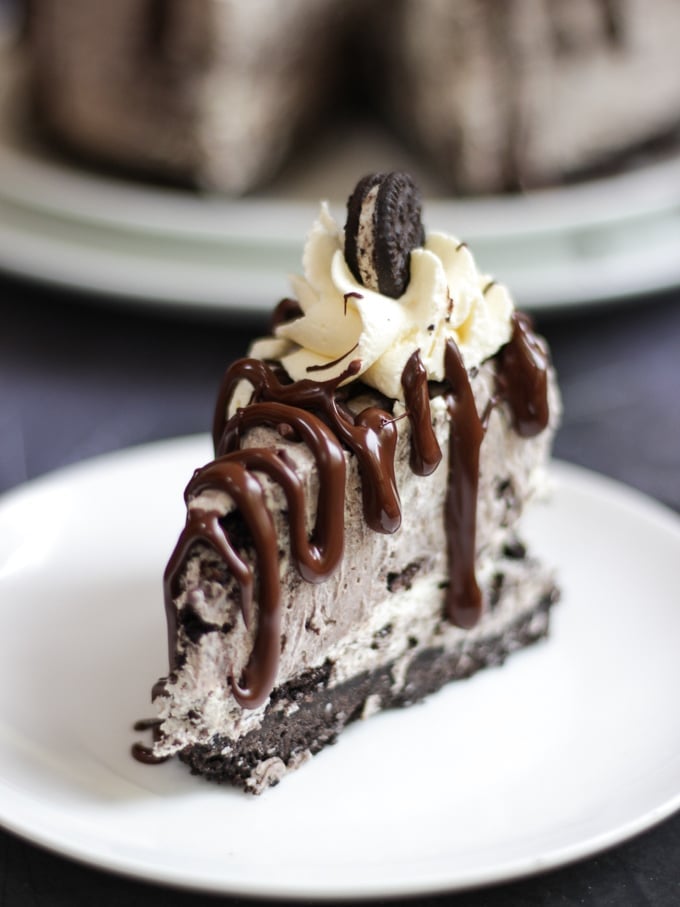 slice of oreo cheesecake topped with whipped cream, chocolate sauce and oreo biscuits