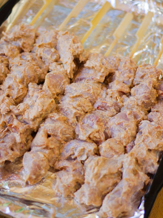 Overhead photo of chicken kebab raw threaded on to bamboo skewers on a grill pan before cooking.