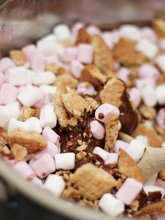 Saucepan with melted chocolate, crushed biscuits and marshmallows for Rolo Rocky Road recipe.