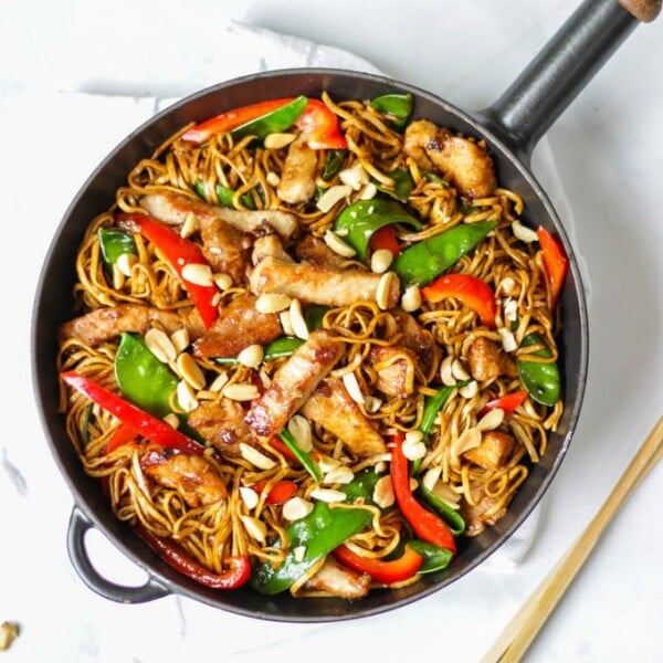 Overhead photo of pork stir fry recipe with noodles, pork, red peppers and mange tout and peanuts.