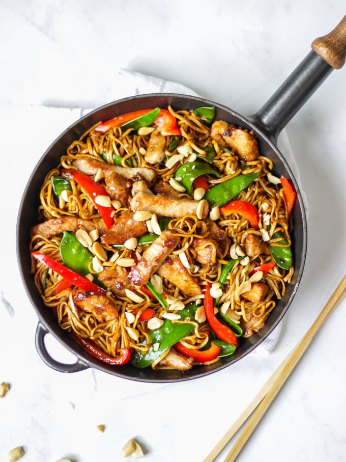 Overhead photo of pork stir fry recipe with noodles, pork, red peppers and mange tout and peanuts.