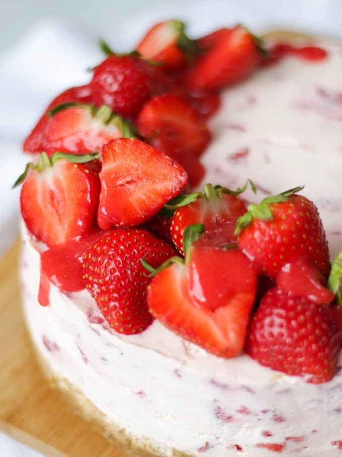 Close up of strawberry cheesecake top with halves strawberries and strawberry coulis drizzle