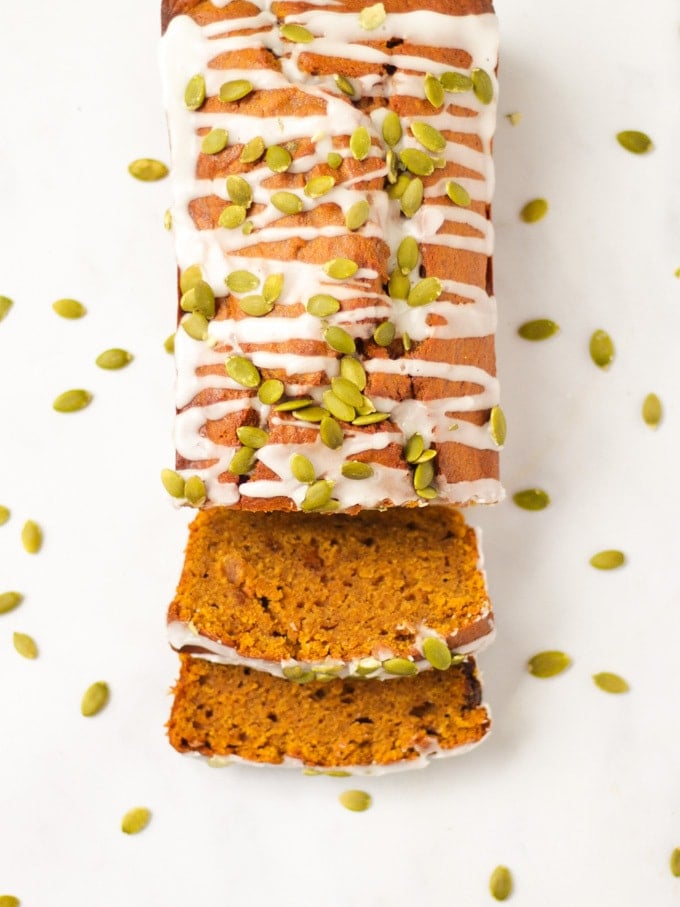 Overhead photo of a pumpkin spice loaf, pumpkin loaf cake, sprinkled with white drizzle icing and pumpkin seeds.