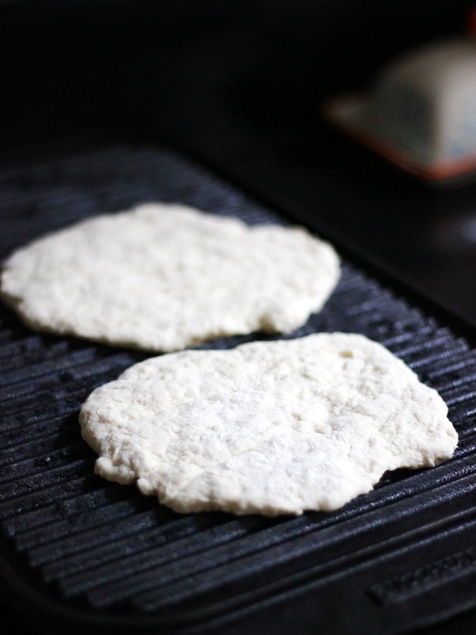 Photo of flatbreads cooking on a black griddle pan.