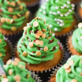 Side photo of green iced Christmas tree cupcakes with sprinkles.
