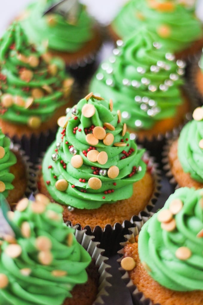 Side photo of green iced Christmas tree cupcakes with sprinkles.