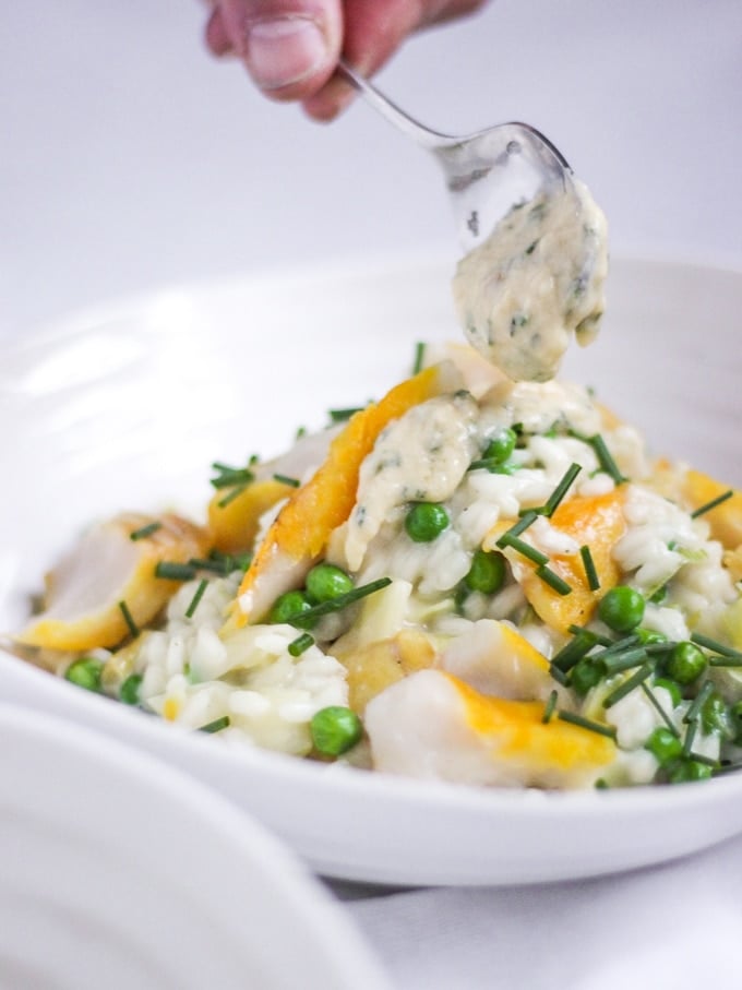 The Saucy Fish Co Smoked Haddock recipe for Smoked Haddock Risotto in bowl with spoon dropping sauce on top topped with chives.