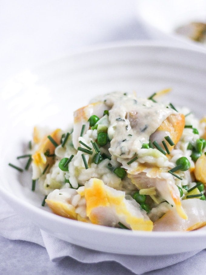 The Saucy Fish Co Smoked Haddock recipe for Smoked Haddock Risotto in a white Sophie Conran bowl topped with chives on white marble background.