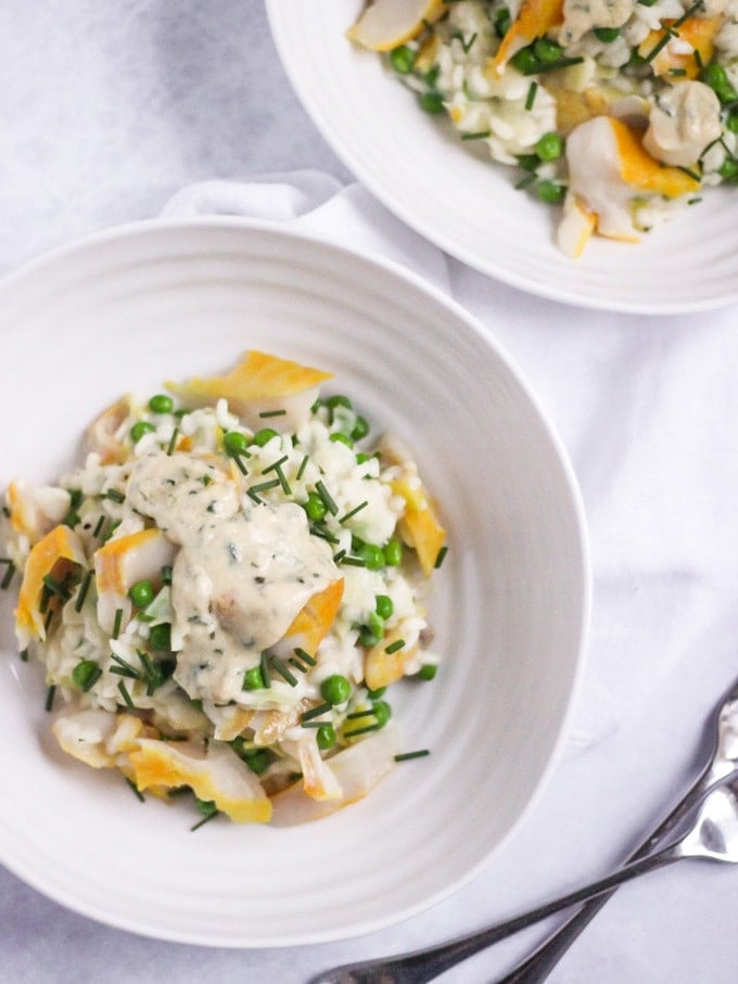 Smoked Haddock Risotto in a white Sophie Conran bowl topped with chives on white marble background overhead shot.