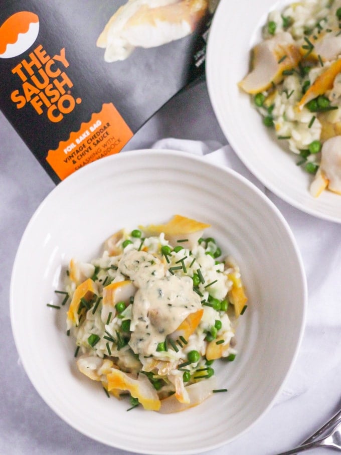 The Saucy Fish Co Smoked Haddock recipe for Smoked Haddock Risotto in a white Sophie Conran bowl topped with chives on white marble background.