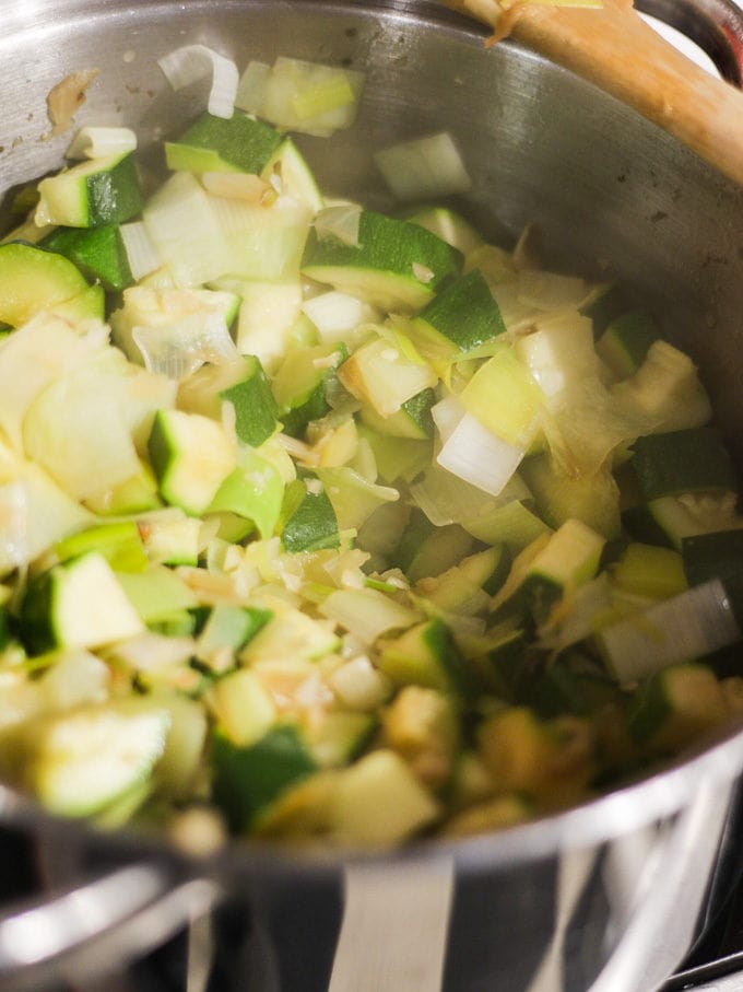 Cubes of courgette cooking in a pan with chopped onions for courgette soup recipe.