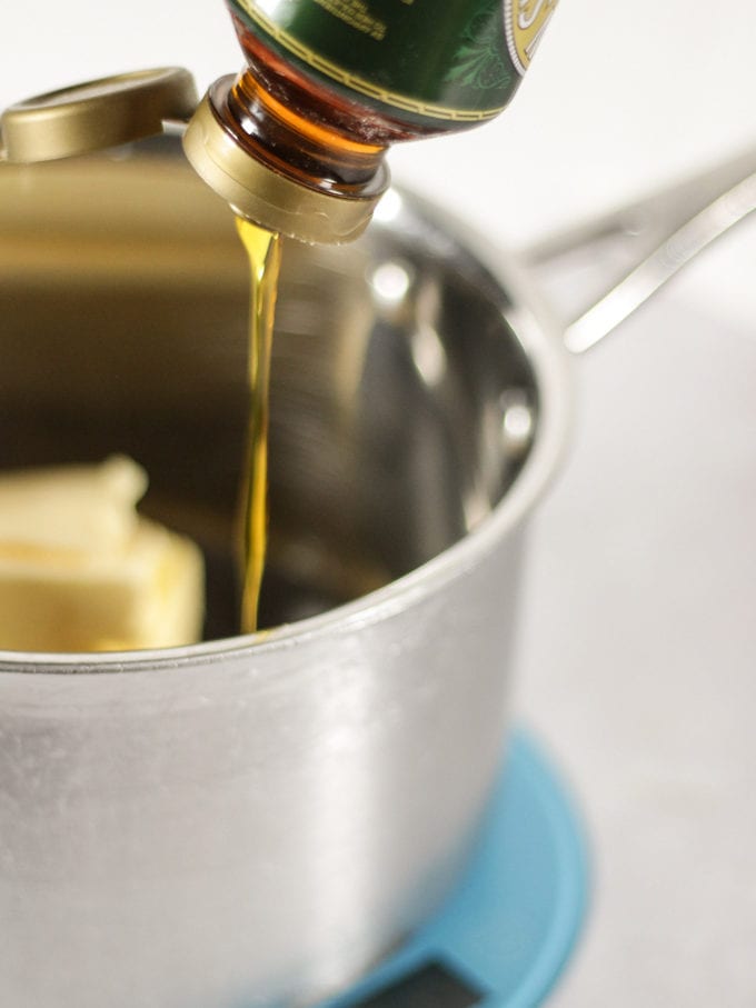 Golden syrup pouring into a metal saucepan on a blue weighing scale.