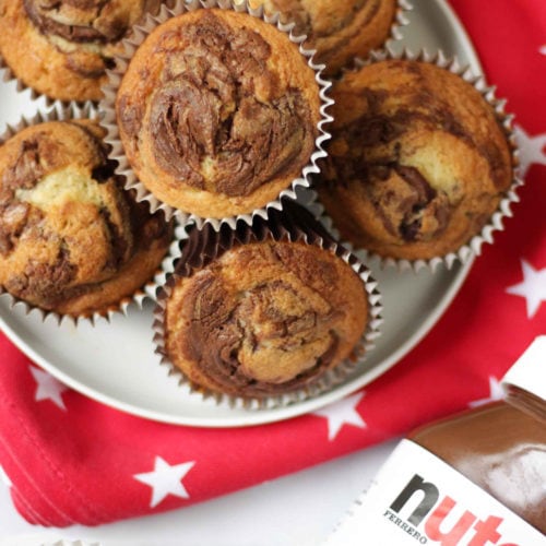 Overhead photo of Nutella Muffins on a white plate on a red tea towel with white stars on with white background.