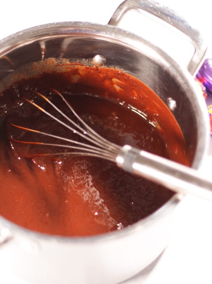 Saucepan of chocolate brownie batter for making Creme Egg Brownies with whisk in.