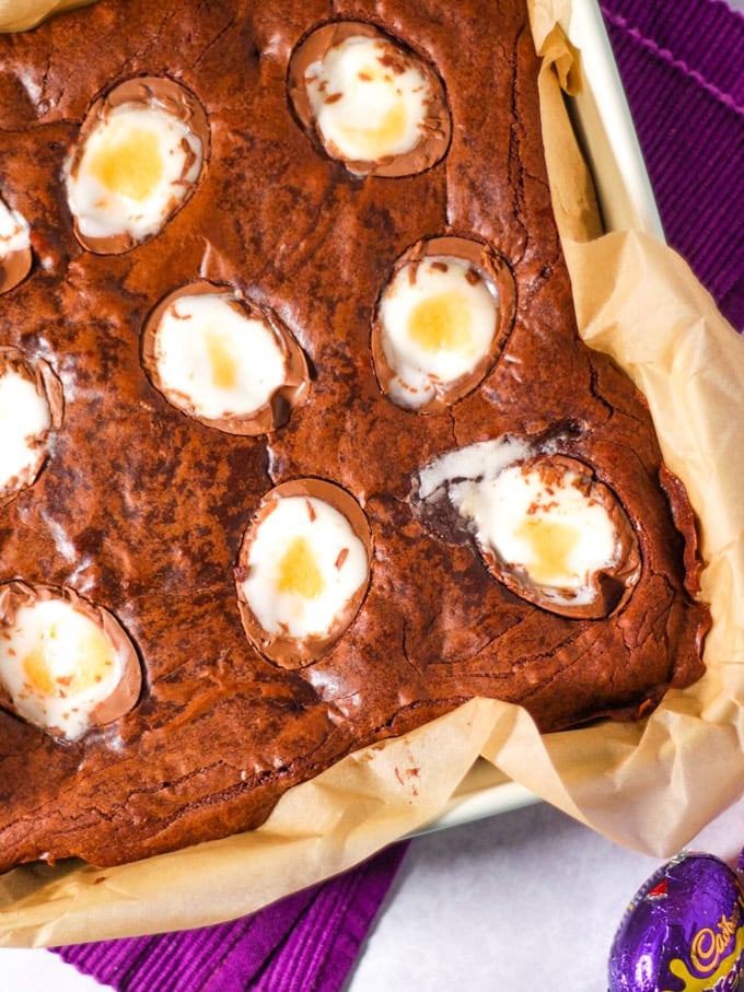 Creme Egg Brownies in baking dish with Creme egg in background.