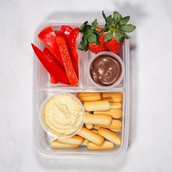 Plastic lunchbox with hummus, breadsticks, strawberries healthy lunch idea for work