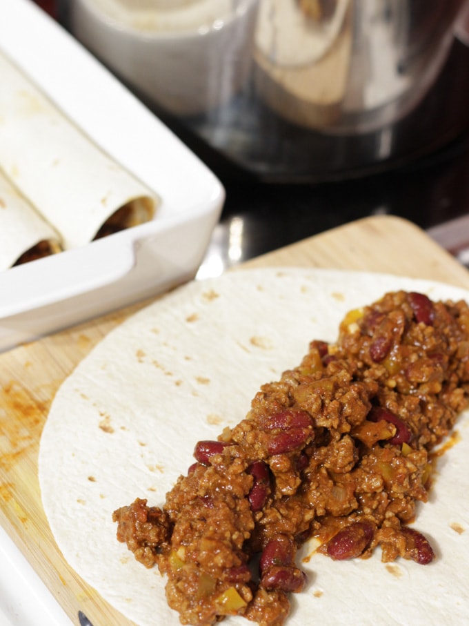 A tortilla wrap laid with Mexican beef filling on top waiting to be rolled.