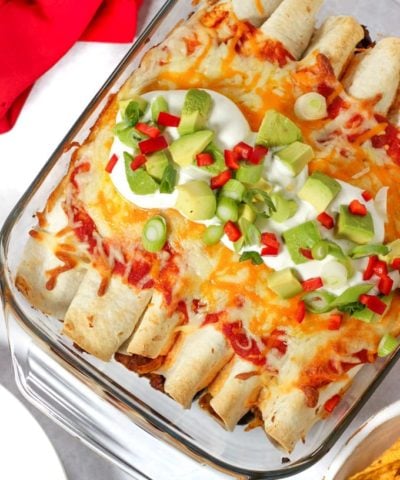 Beef enchiladas topped with cheese and avocado and chilli