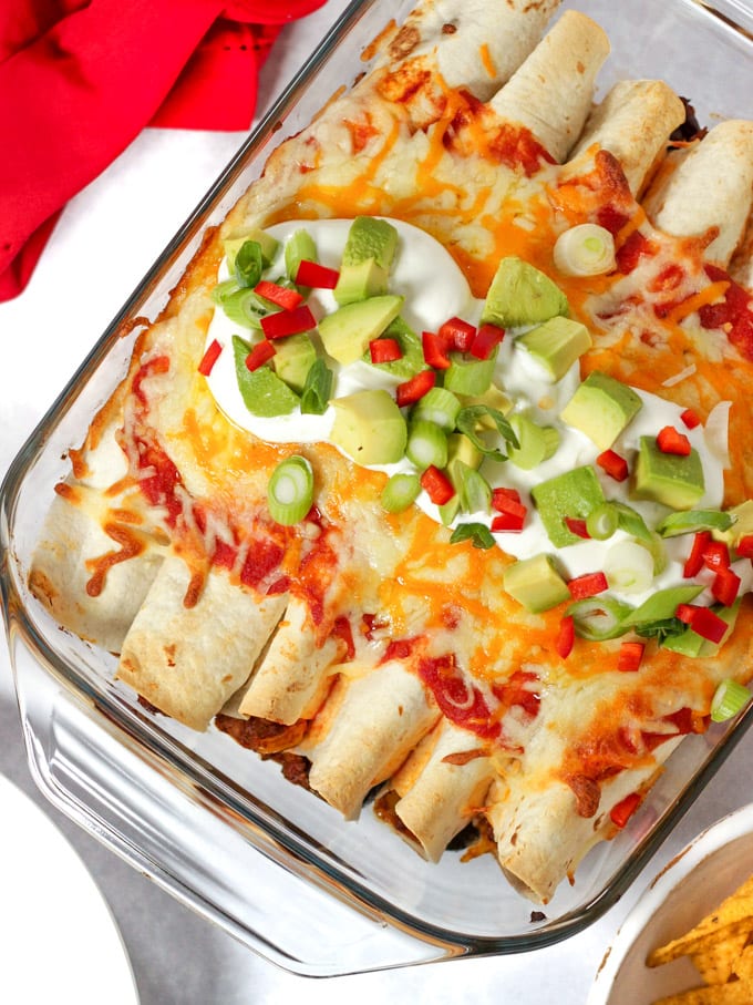 Beef enchiladas topped with cheese and avocado and chilli